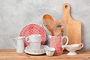 Kitchen utensils and tableware on wooden table over rustic grey background