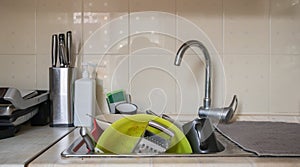 The kitchen utensils in the wash basin need to be washed. A pile of dirty dishes in the kitchen sink. Kitchen utensils need