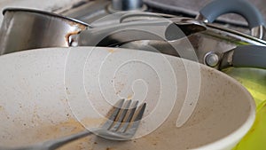 The kitchen utensils in the wash basin need to be washed. A pile of dirty dishes in the kitchen sink. Kitchen utensils need