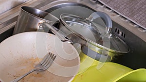 The kitchen utensils in the wash basin need to be washed. A pile of dirty dishes in the kitchen sink. Kitchen utensils need