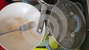 The kitchen utensils in the wash basin need to be washed. A pile of dirty dishes in the kitchen sink. Kitchen utensils need