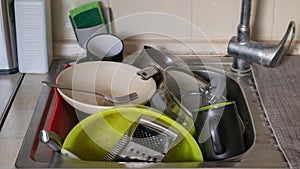 The kitchen utensils in the wash basin need to be washed. A pile of dirty dishes in the kitchen sink. Kitchen utensils need