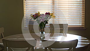 Kitchen view of white table and chairs with flowers on center zooming in