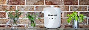 Kitchen waste compost pot and reused jars and tin on kitchen shelf