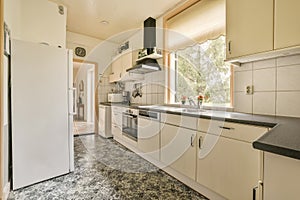 a kitchen with white cabinets and a large window