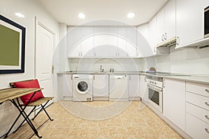 Kitchen with white furniture and appliances covering two walls,