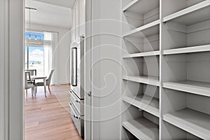 Kitchen with a white refrigerator and a white pantry with shelves
