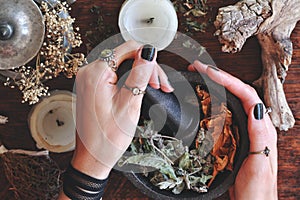 Kitchen witchery - female wiccan witch holding pestle and mortar in her hands, making magickal herb blend for a spell photo