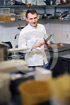 Kitchen worker sharpens a large professional knife