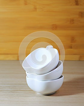 Kitchenware, 3 white ceramic bowls of apple shape design on wood dining table background