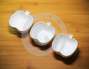 Kitchenware, 3 white ceramic bowls of apple shape design on wood dining table background-soft focus