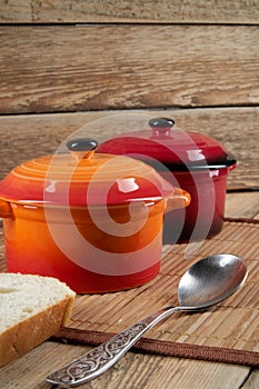 Kitchenware. Colored ceramic saucepans on wooden background