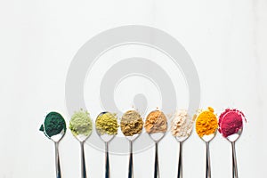 Kitchenware with different colorful superfood powders on wooden table photo