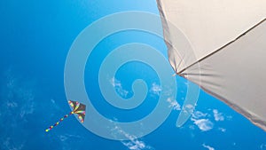 Kite blue sky. Colorful high flying toy. Air kite fly on wind clouds. Rainbow kite in summer background. Concept of