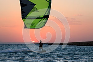 Kite boarder sportsman under sunset sun, freestyle kiteboarding rider on the evening kitesession, sunset in the sea, extreme