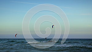 Kite boarder surfing in sea. Young active people kite surfing on big sea waves