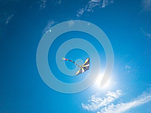 Kite clouds. Colorful high flying toy. Air kite fly on blue wind sky background with copy space. Rainbow summer kite