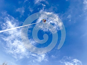 Kite flying in a blue sky with a scary cloud skull
