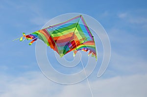 Kite with multicolored stripes of the rainbow flies high in the photo