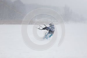 Kite surfer being pulled by his kite across the snow