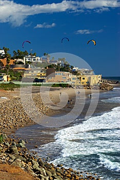 Kite surfers enter the water along the rocky shore