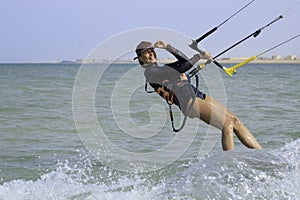 Kite surfing girl in sexy swimsuit with kite in sky on board in blue sea riding waves with water splash. Recreational activity,