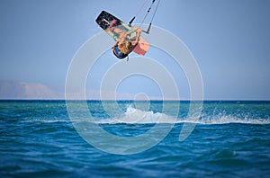 Kite surfing girl in sexy swimsuit with kite in sky on board in blue sea riding waves with water splash. Recreational activity,