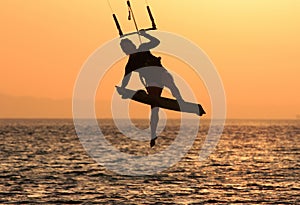Kite surfing girl in swimsuit with kite in sky on board in blue sea riding waves with water splash. Recreational activity,