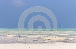 Kite surfing on tropical beach, low tide. Kite surfers on the sea. Scenic Indian Ocean with kite boards, Zanzibar, Paje beach.