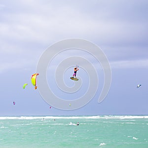 Kiteboarding. Fun in the ocean. Extreme Sport Kitesurfing. Kitesurfer jumping high in the air performing triks during
