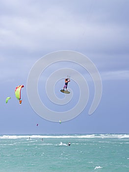 Kiteboarding. Fun in the ocean. Extreme Sport Kitesurfing. Kitesurfer jumping high in the air performing triks during