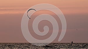 Kiteboarding kitesurfing kiteboarder kitesurfer kites silhouette in the ocean on sunset