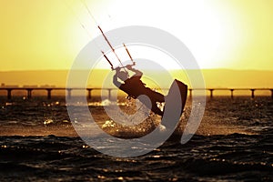 Kiteboarding sportsman silhouette, sunset in the sea