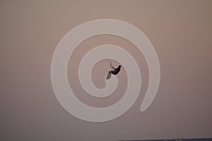 Kiter jumps high above the water at sunset