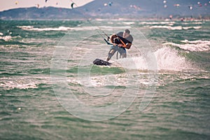 Kiter makes the difficult trick on a beautiful background. Kitesurfing Kiteboarding action photos man among waves