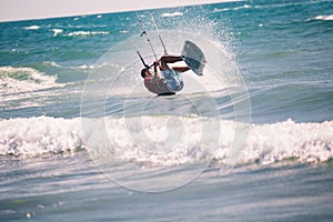 Kiter makes the difficult trick on a beautiful background. Kitesurfing Kiteboarding action photos man among waves