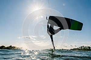 Kitesurfer jumping and doing a trick with beautiful sun star behind