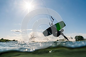 Kitesurfer sliding with his hand in the water photographed half underwater