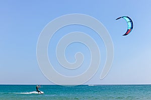 A kitesurfer surfing on the smooth azure water. recreational sport. A Man Rides A Kiteboarding In The Sea Water. extreme