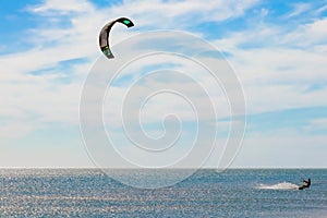 A kitesurfer surfing on the smooth azure water. recreational sport. A Man Rides A Kiteboarding In The Sea Water. extreme