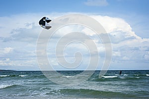 Kitesurfers ride kites on Black Sea at sandy Beach In Bulgaria, Sozopol on sunny day at sunset on blue sky and clouds background.