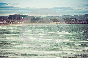 Kitesurfing man in action on stormy sunset evening at Brusand Beach, Norway.