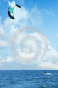 Kitesurfing riding over a surface of sea with a parachut. Summer