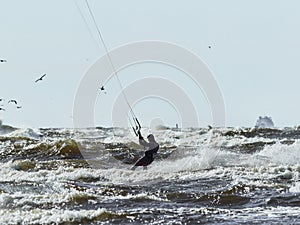 Kitesurfing in stormy sea. Kitesurfer on the waves in the sea