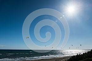 Kitesurfing under a shinny bright sun in blue sky.