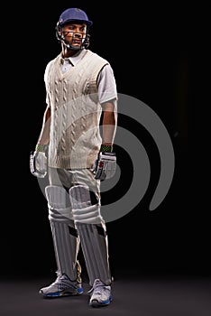 Kitted up. A cropped shot of an ethnic young man in cricket attire isolated on black.