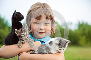 Kitten on arm of the boy outdoors, child huge his love pet