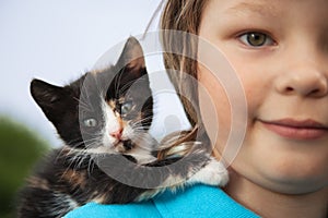 Kitten on arm of the boy outdoors, child huge his love pet