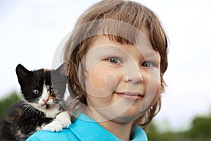 Kitten on arm of the boy outdoors, child huge his love pet