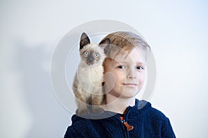 Kitten sits on a boy of 8 years old on his shoulder